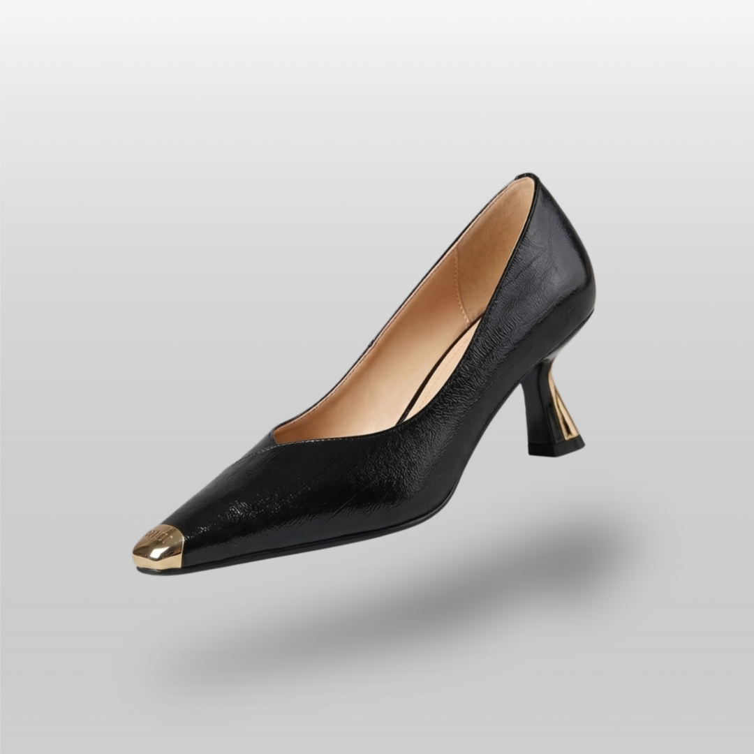 Black high-heeled shoe with gold tip on a light gray background
