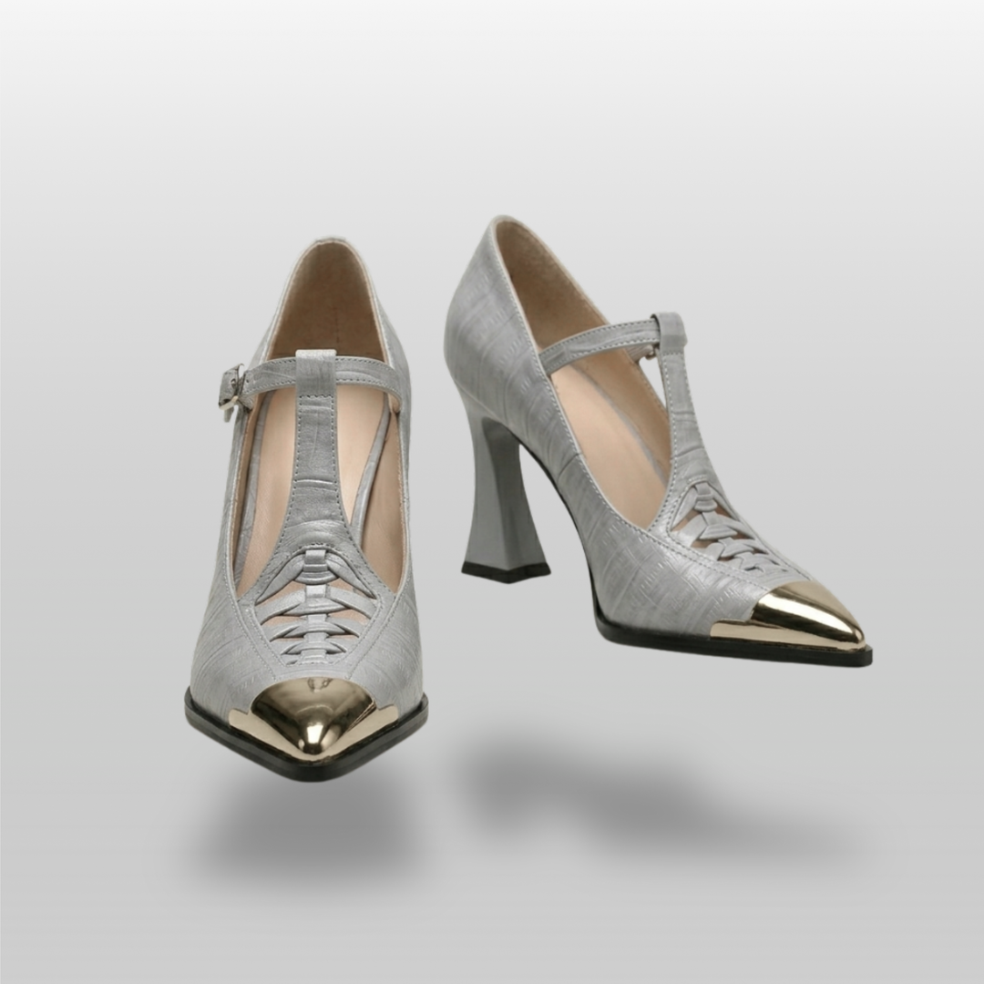 Pair of silver high-heeled shoes with gold toes on a light gray background
