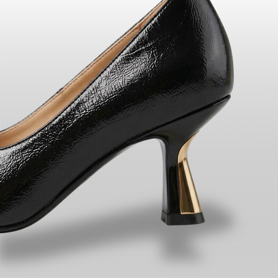 Black high-heeled shoe with gold heel on a light gray background
