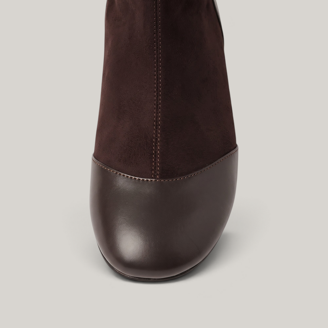 Close-up of rounded leather toe cap joined to napped brown shaft