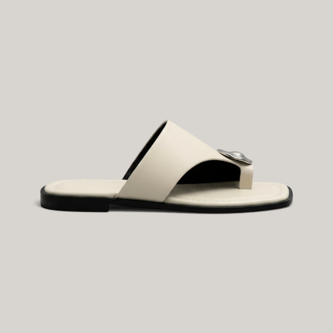 Cleo Sandal in Ivoire Argenté. Lateral profile showing the single ivory band, molten silver medallion and flat sole.