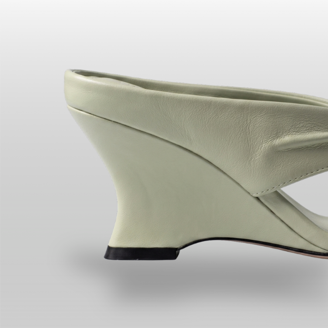 Close-up of sculptural wedge heel geometry in sage green