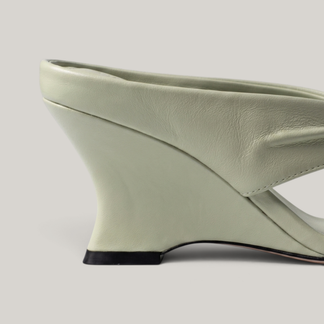 Close-up of sculptural wedge heel geometry in sage green