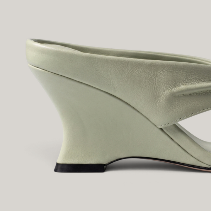 Close-up of sculptural wedge heel geometry in sage green