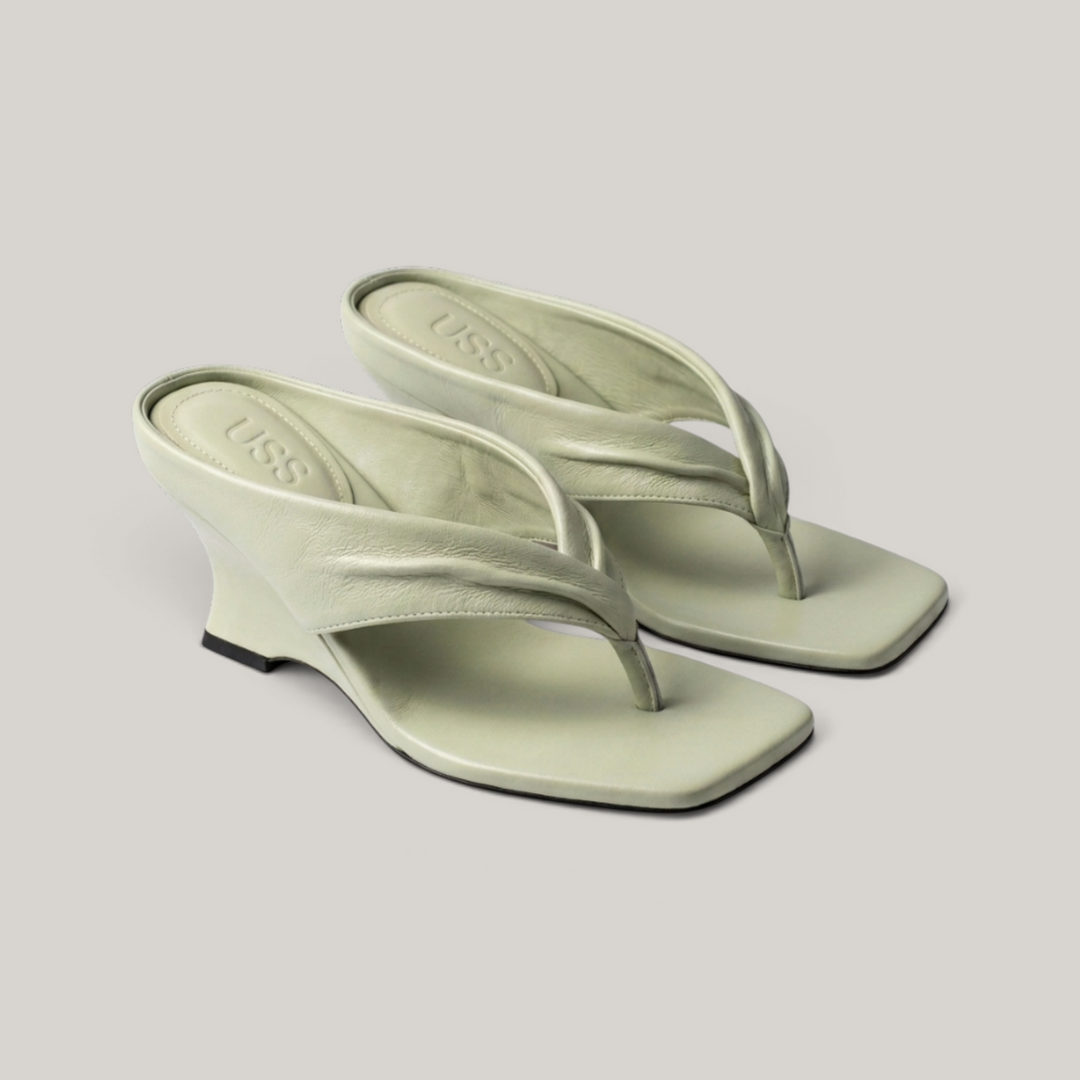 Pair of sage green sculptural wedge sandals, symmetrical view