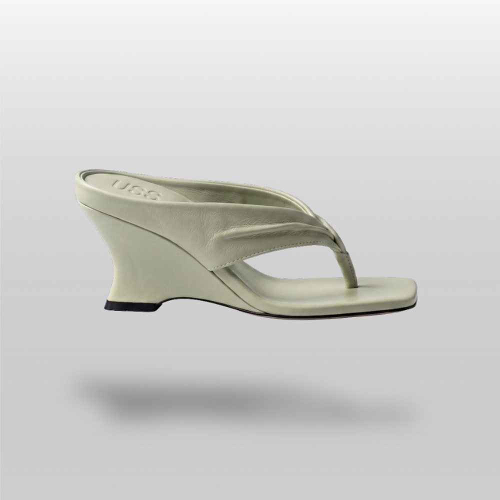 Side profile of continuous sculptural wedge heel in sage green