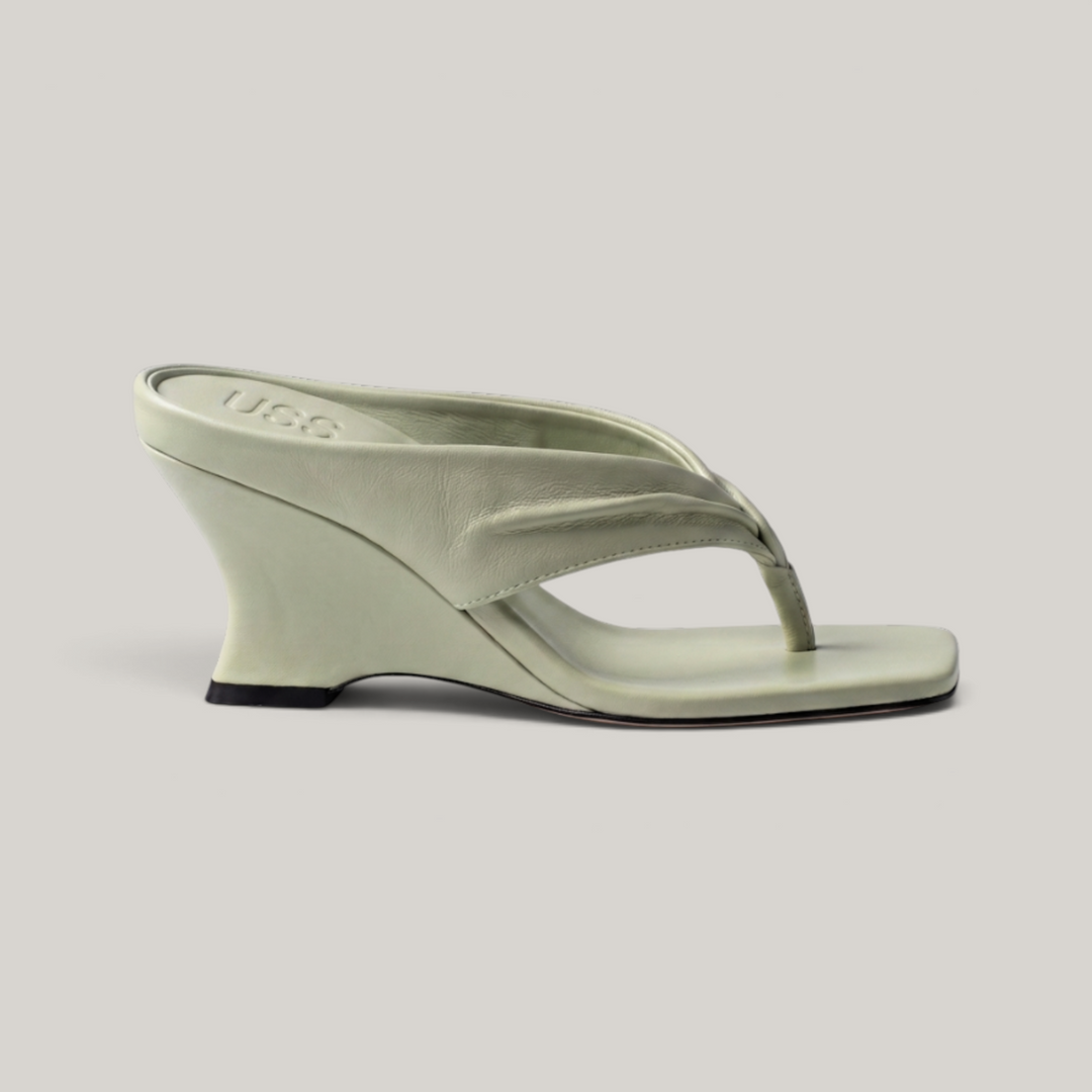 Side profile of continuous sculptural wedge heel in sage green