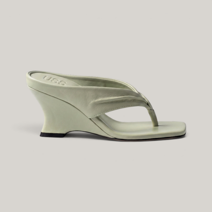 Side profile of continuous sculptural wedge heel in sage green