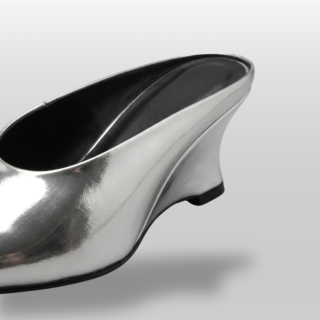 Close-up detail of the sculptural wedge heel on the Lumière Mule in metallic silver Argent Vif.
