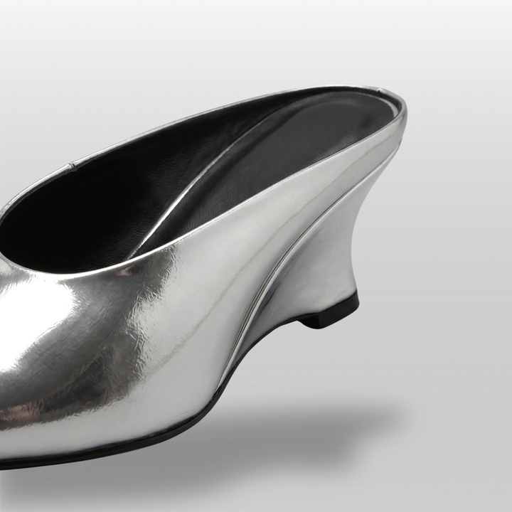 Close-up detail of the sculptural wedge heel on the Lumière Mule in metallic silver Argent Vif.