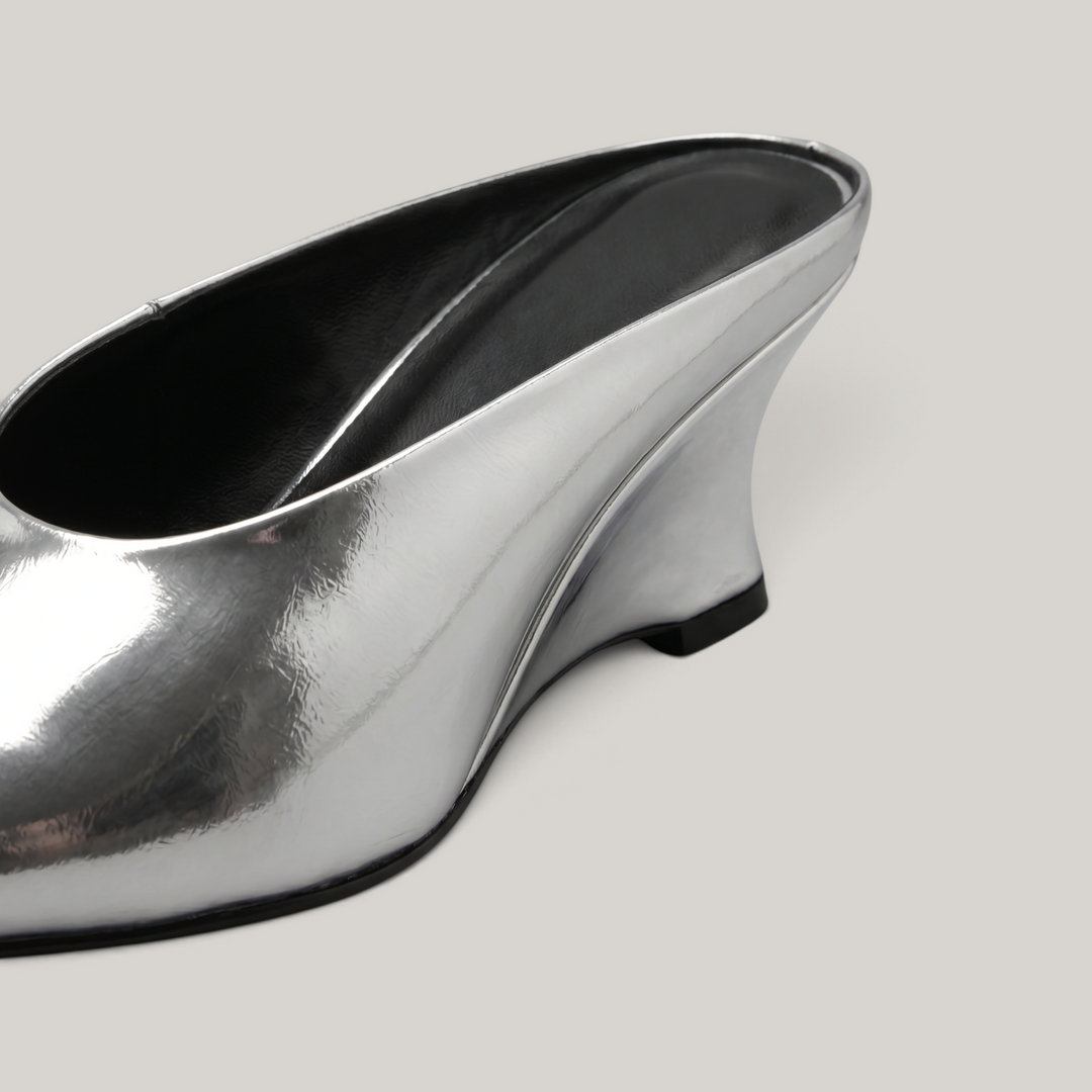 Close-up detail of the sculptural wedge heel on the Lumière Mule in metallic silver Argent Vif.