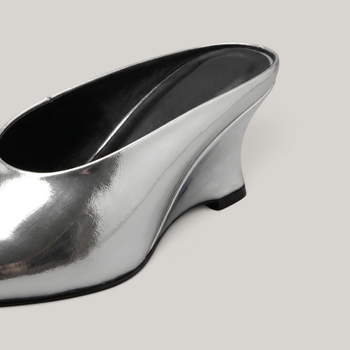 Close-up detail of the sculptural wedge heel on the Lumière Mule in metallic silver Argent Vif.