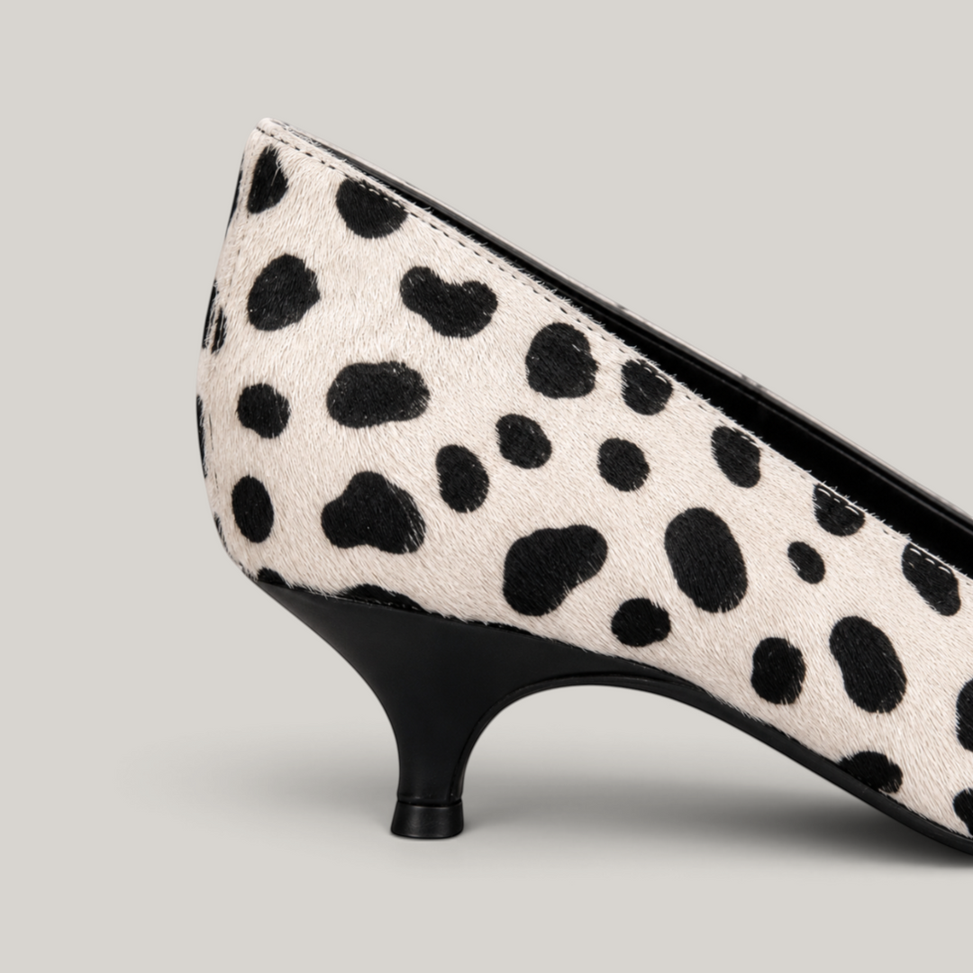 Close-up of curved black kitten heel against spotted ivory upper