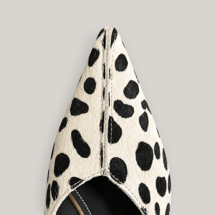 Close-up of elongated pointed toe with irregular black spots on ivory