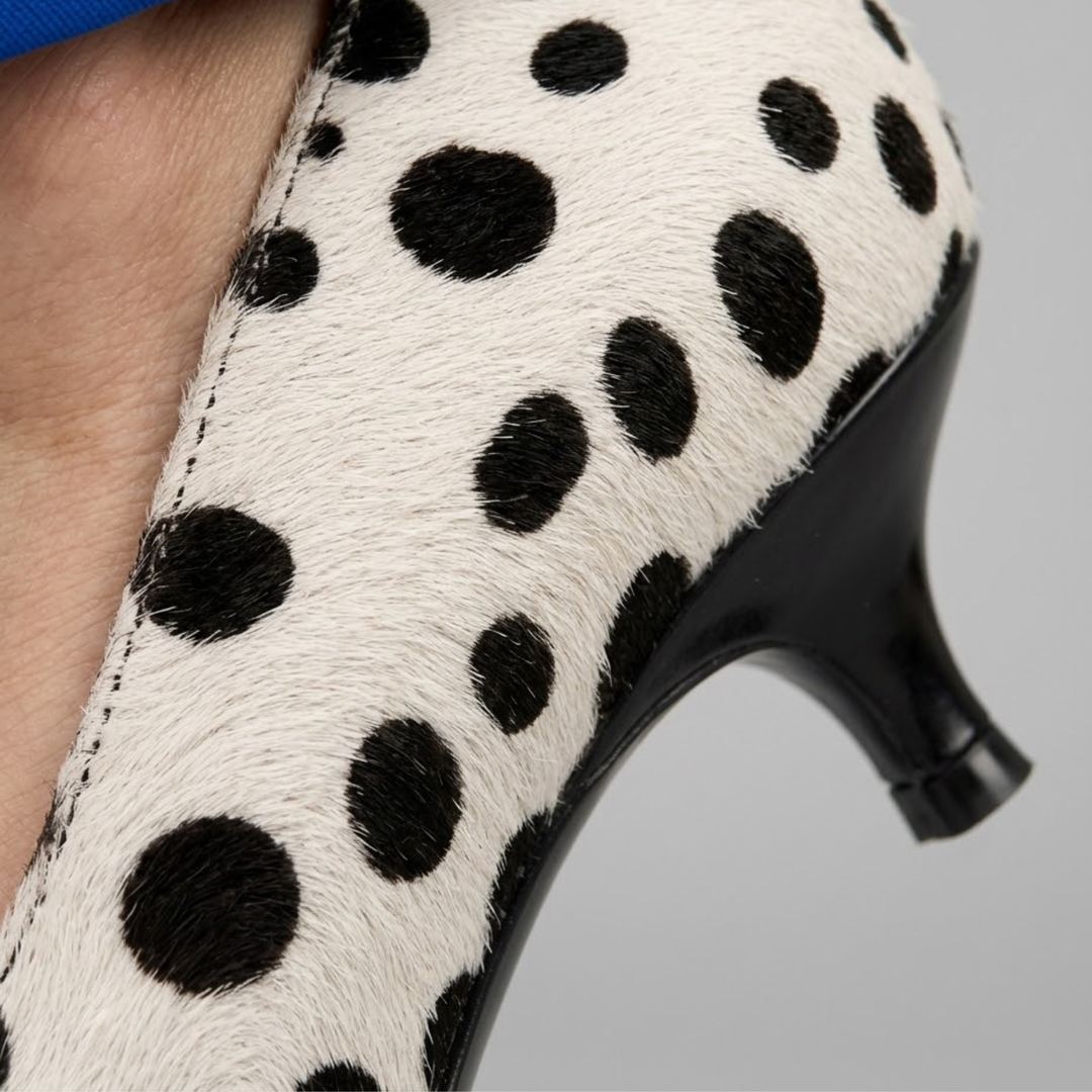 Close-up of spotted ivory pump worn with cobalt blue trousers