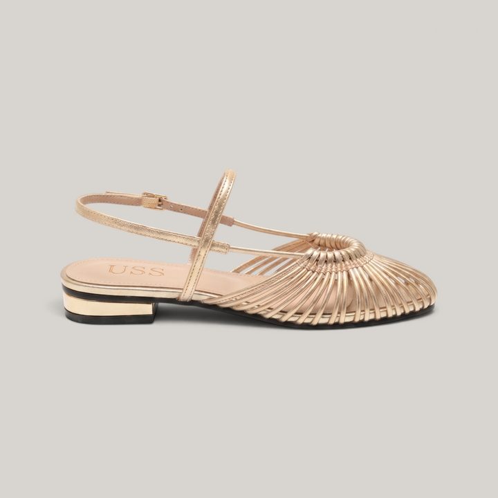 Side profile of gold woven flat sandal with gold-trimmed block heel