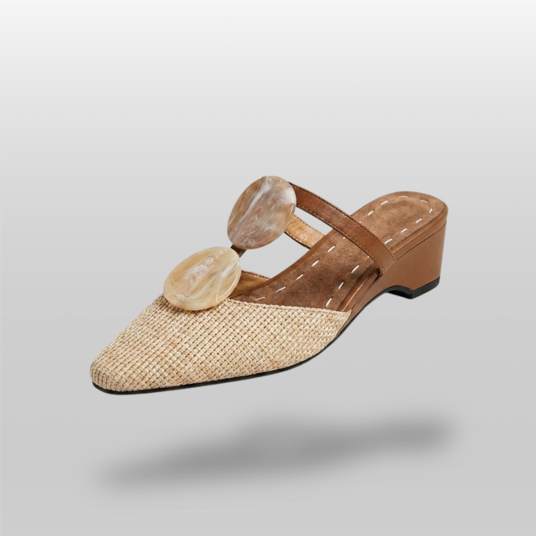Paloma Mule in Sable Doré. Natural raffia woven vamp, two oval marbled resin medallions, camel leather T-strap and 3cm wedge.
