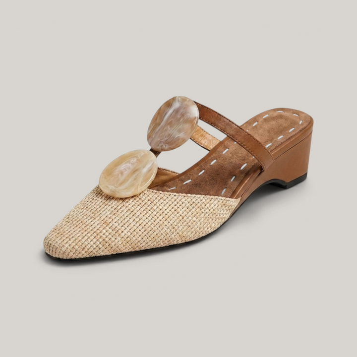 Paloma Mule in Sable Doré. Natural raffia woven vamp, two oval marbled resin medallions, camel leather T-strap and 3cm wedge.