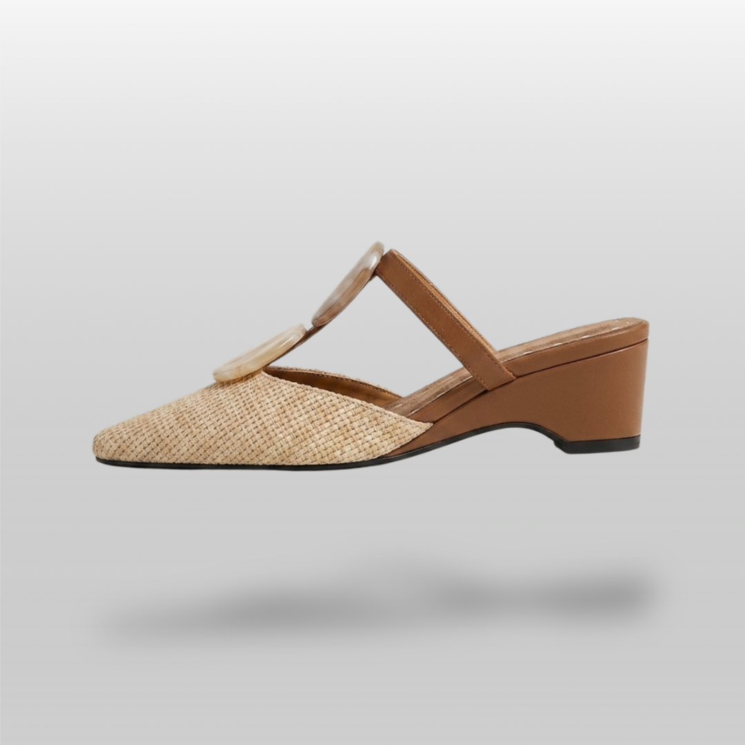 Paloma Mule in Sable Doré. Lateral silhouette showing the soft square toe, raffia upper, resin medallions and continuous camel wedge.