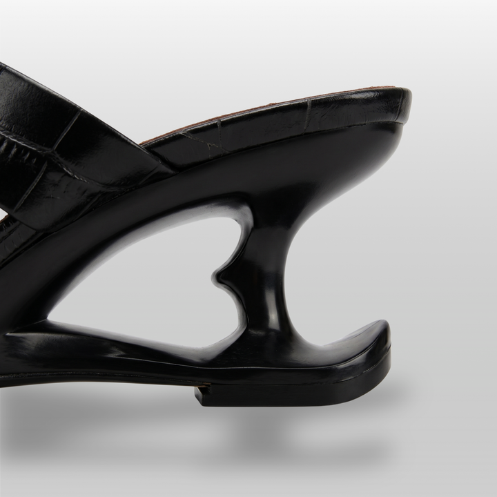 Sculpture Sandal in Noir Croco. Detail of the architectural 6cm negative-space cut-out heel.