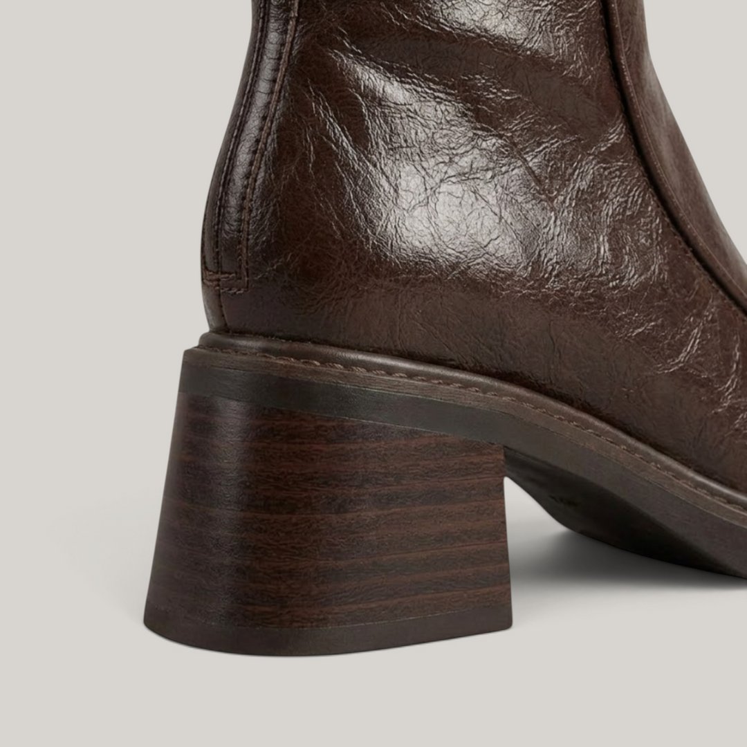 Close-up of stacked wood-grain block heel on brown knee-high boot