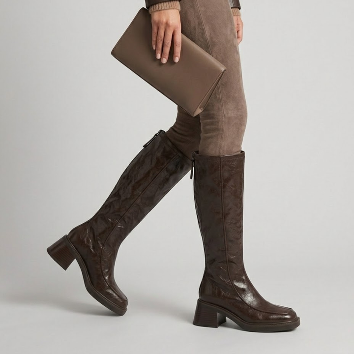 Brown knee-high boots worn mid-stride with taupe suede tailoring