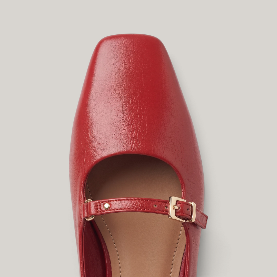Close-up of soft square toe and gold buckle strap on red flat