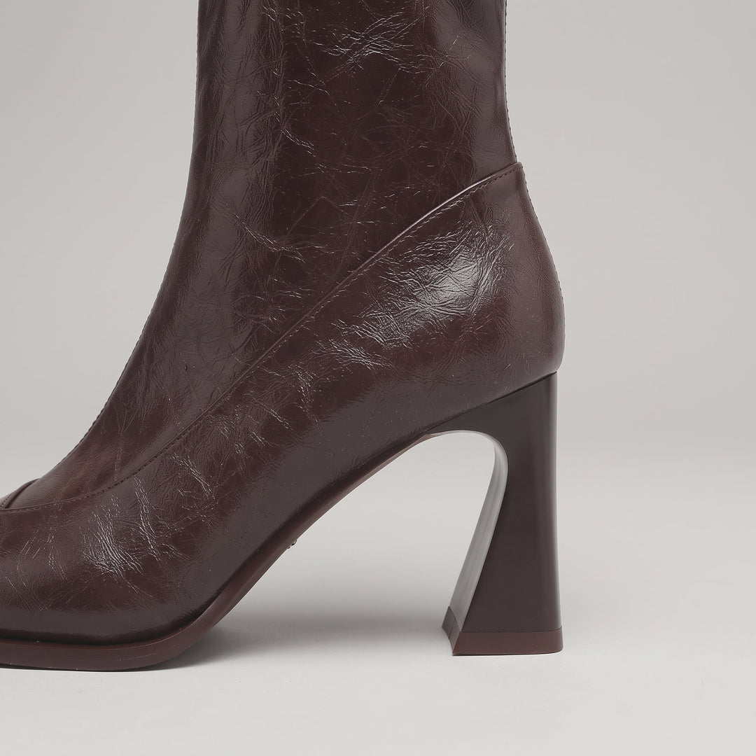 Sculpted flared heel of the Vienne Bootie in Moka Ciré, curving in at the back and widening at the base