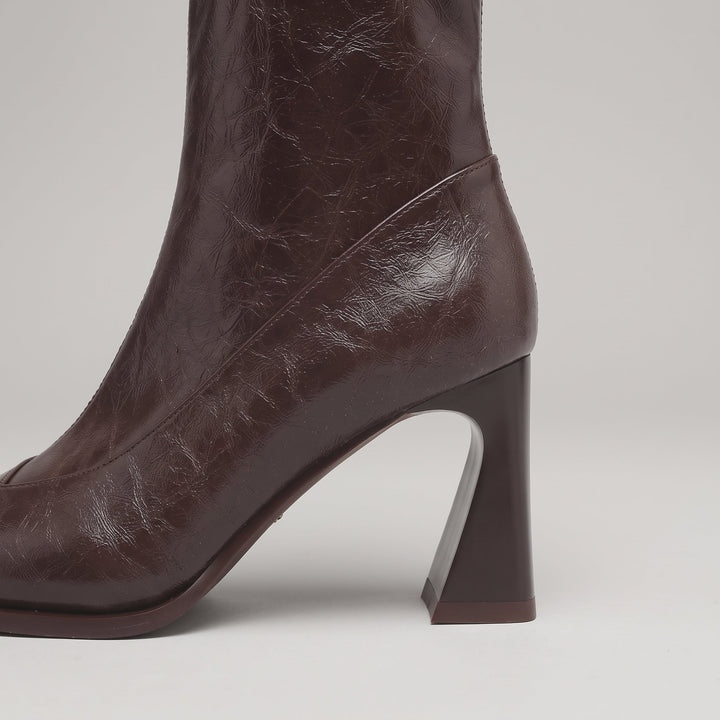 Sculpted flared heel of the Vienne Bootie in Moka Ciré, curving in at the back and widening at the base