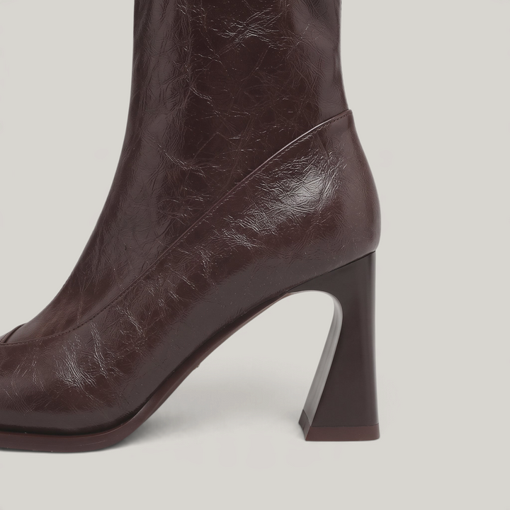 Sculpted flared heel of the Vienne Bootie in Moka Ciré, curving in at the back and widening at the base