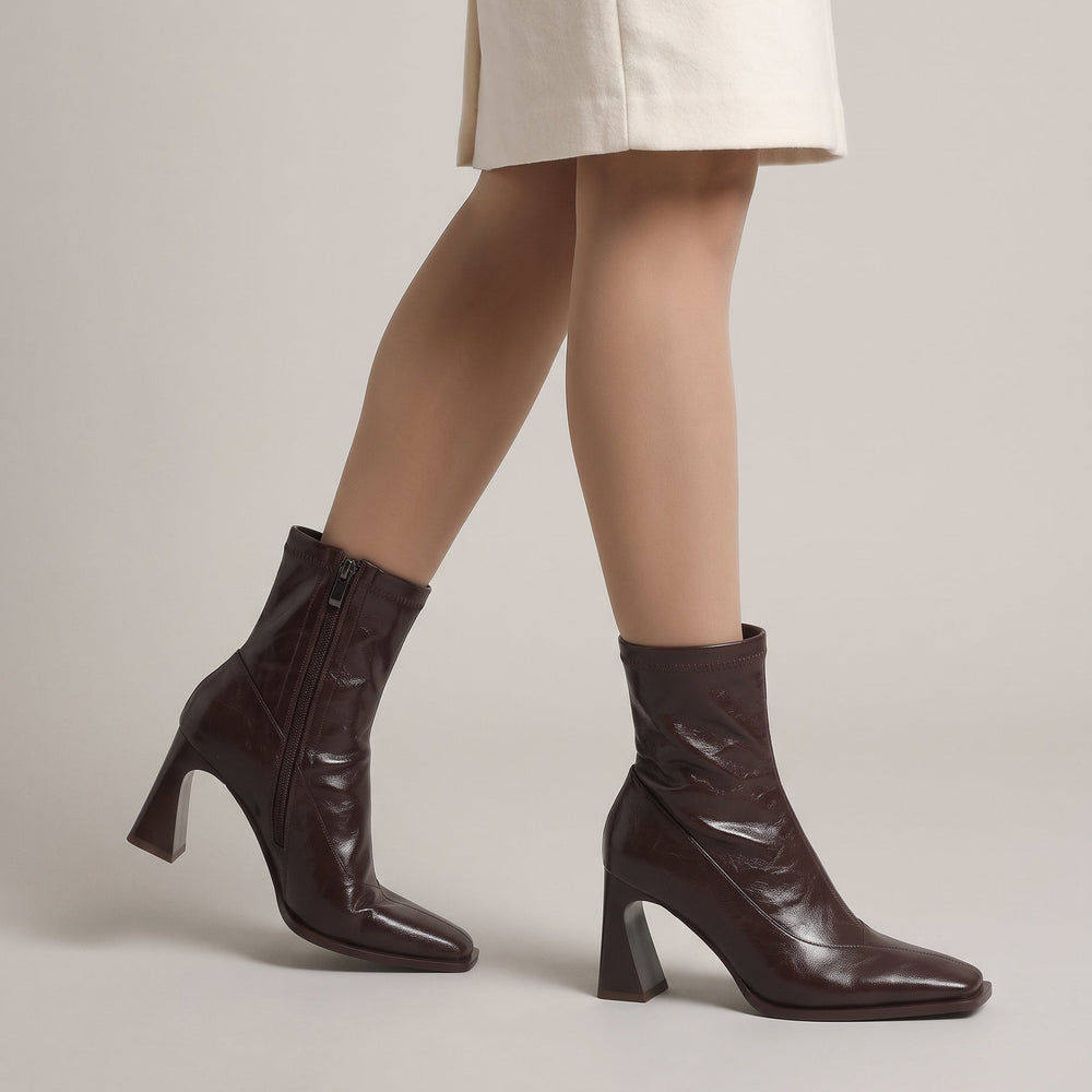 Vienne Bootie in Moka Ciré worn with an ecru wool skirt, showing the flared heel and square toe
